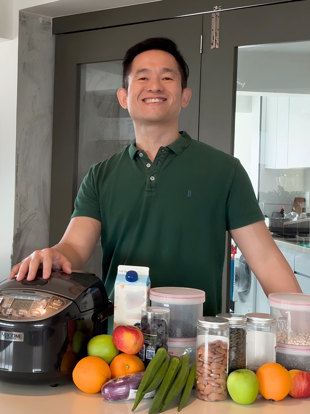 Chung Chen smiling in his kitchen with fresh fruits, vegetables, and nuts